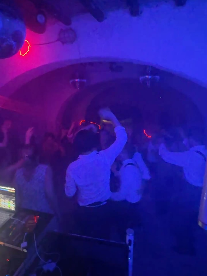 A crowded wedding dance floor lit in blue and purple